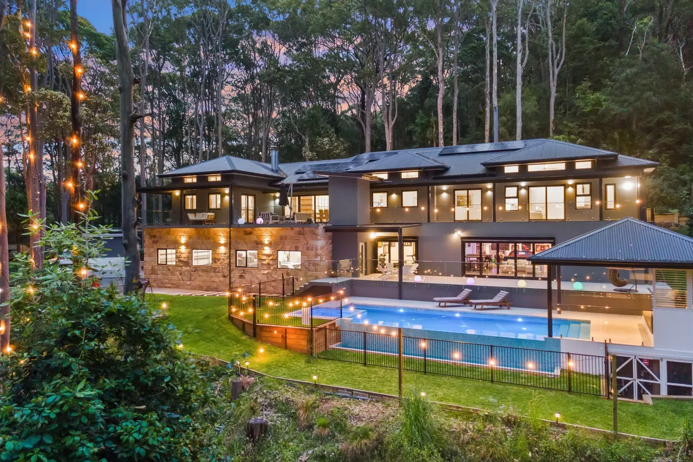 Rear of the home with the pool and garden at dusk